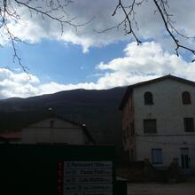El Santuari de la Salut, dalt de la cinglera, vist des de la vall d'Hostoles