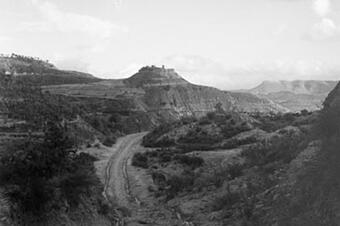 Paisatge dels voltants el 1931: camins de terra, conreus i turons, amb el castell al fons.