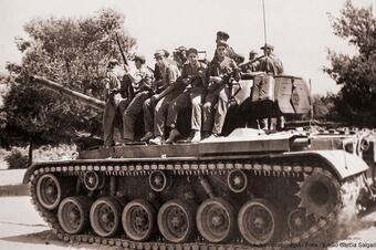 <p>Tanc del campament militar de Mas d'Enric, amb soldats a la torreta.</p> Memòria en ruta al Catllar – Tanc del campament militar de Mas d'Enric, amb soldats a la torreta