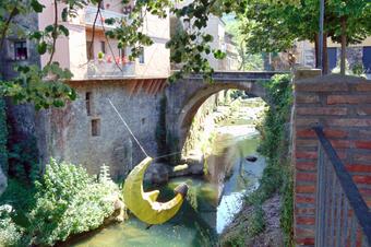 <p>Foto: Josep Maria Viñolas Esteva, CC BY-SA 4.0, via Wikimedia Commons</p> Escultura del Pescallunes i pont sobre el Brugent, Sant Feliu de Pallerols