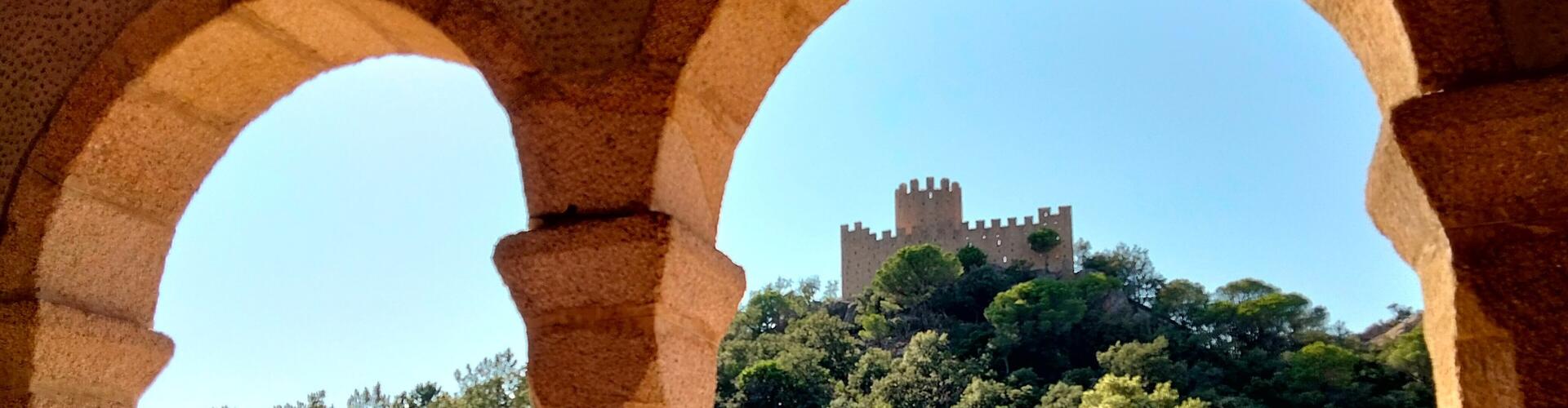 Castell de Farners vist entre les arcades del porxo del santuari, Santa Coloma de Farners